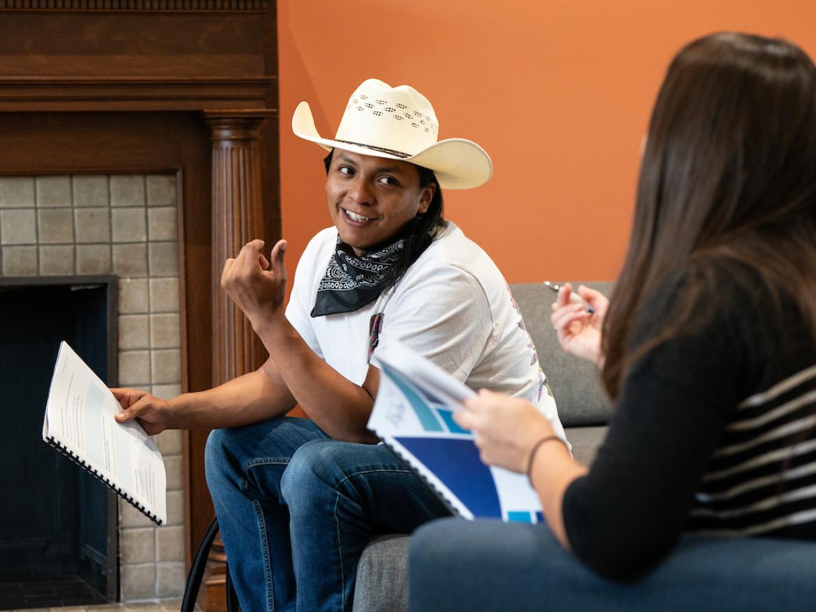 A young man wearing a cowboy hat sits and talks with a young women as they strategize before going on a Congressional lobby visit