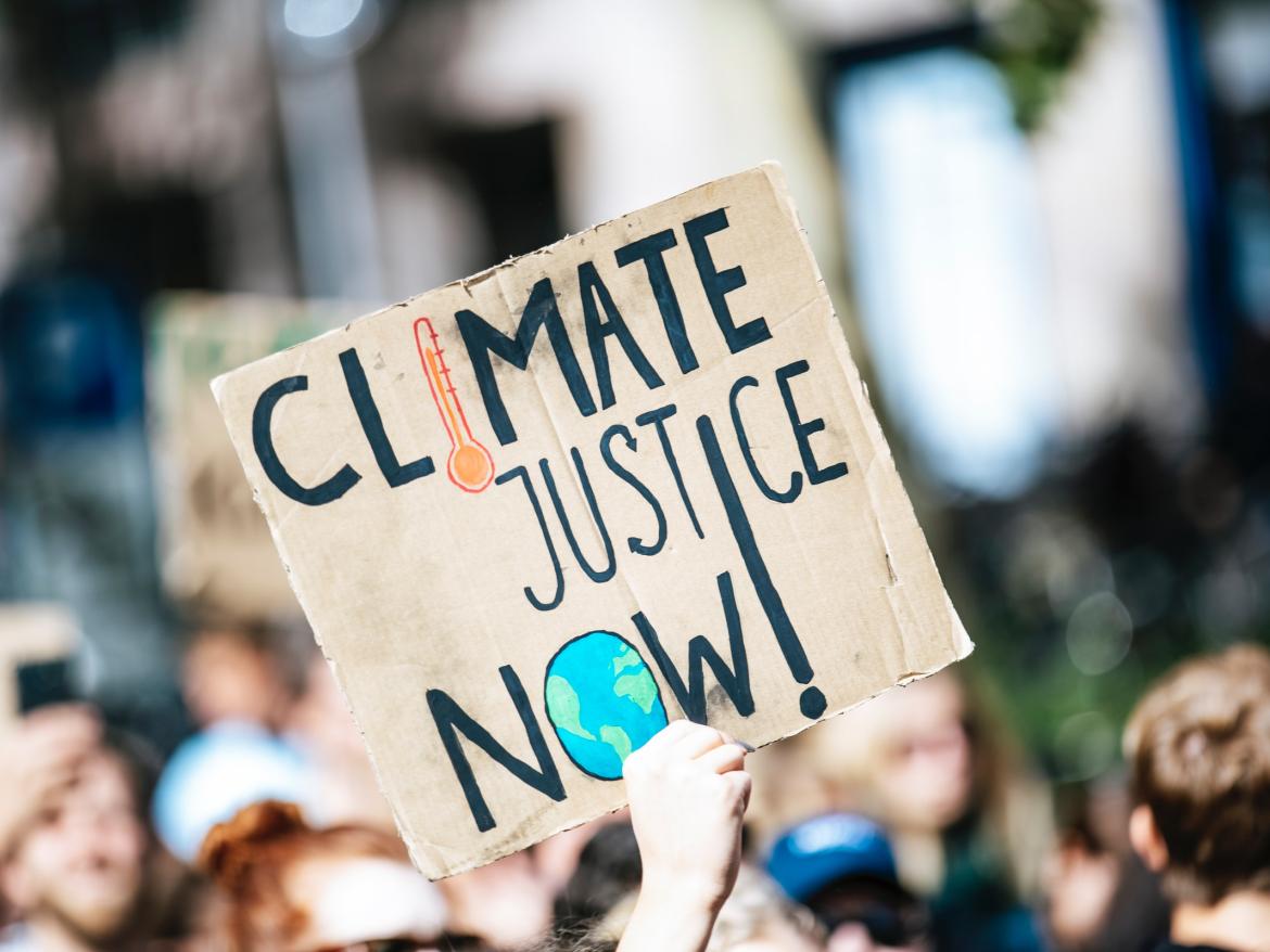 Protestor holds "Climate Justice Now" sign
