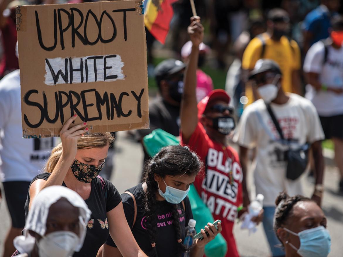 Woman holding "Uproot White Supremacy" sign at protest