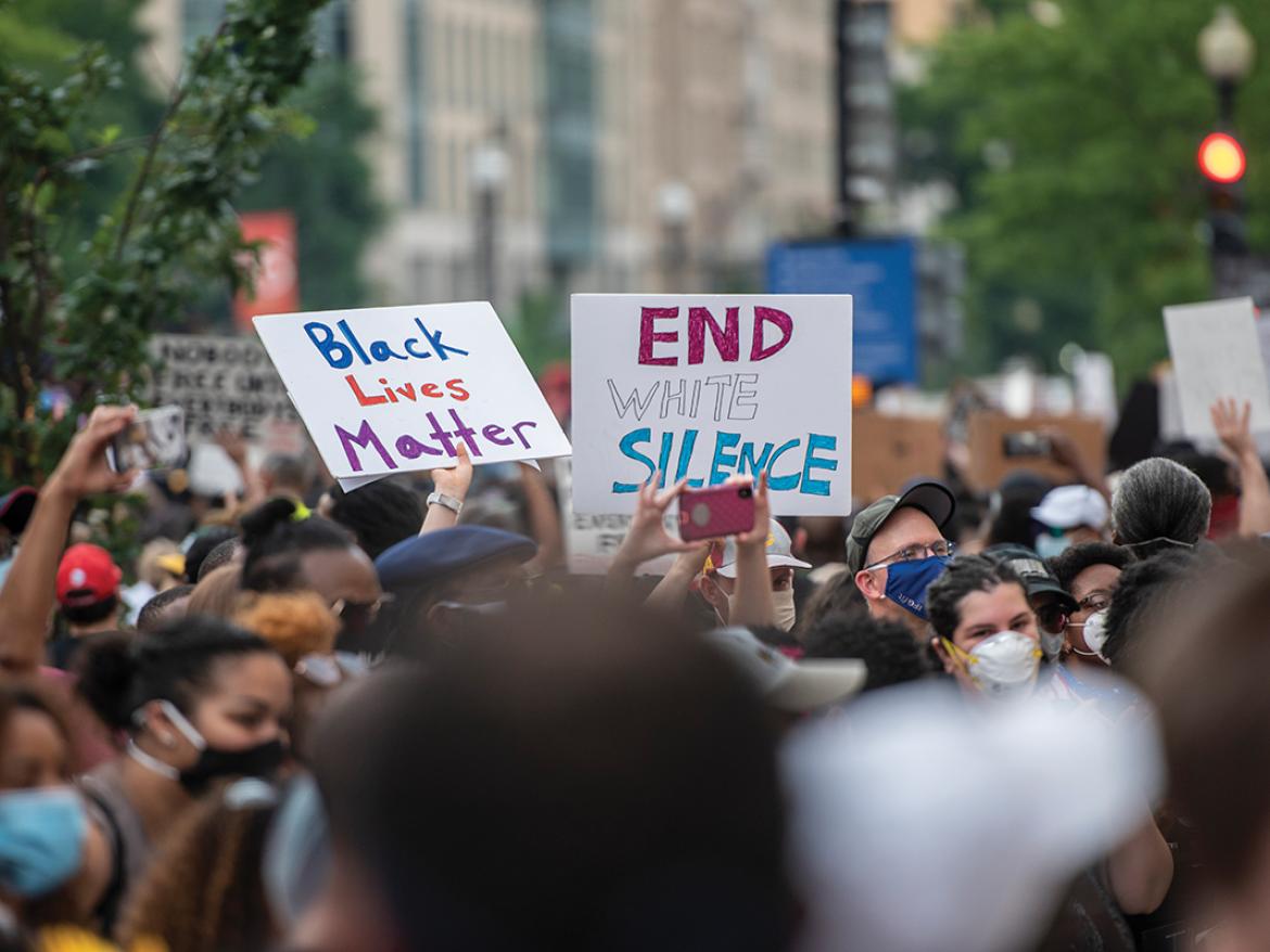 Protestors hold signs that read "Black Lives Matter" and "End white silence"