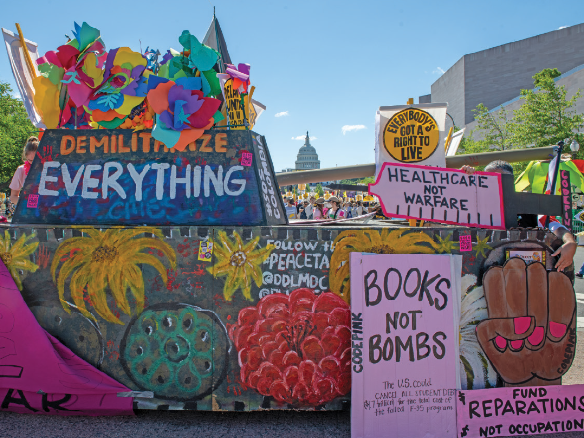 A mock tank built for a protest reads, "Demilitarize Everything."
