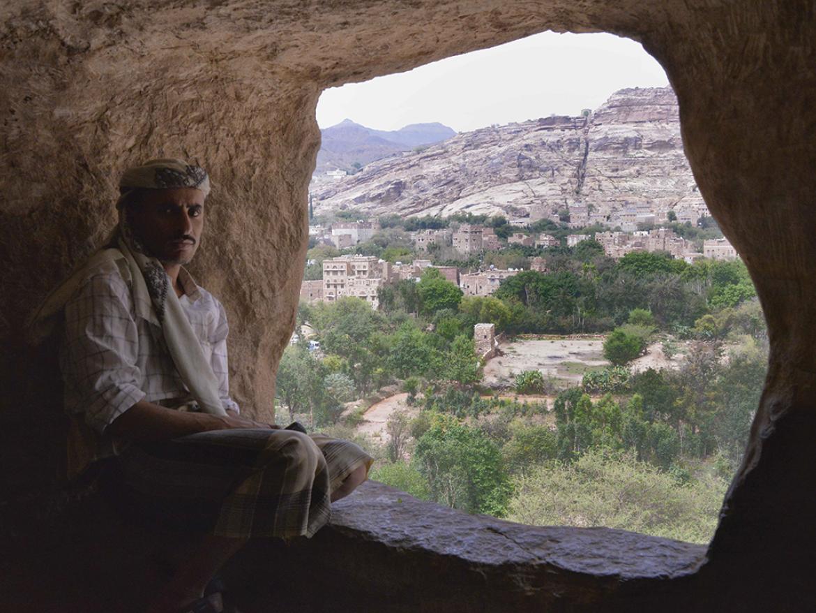 Yemen: Man sitting at mouth of cave overlooking landscape