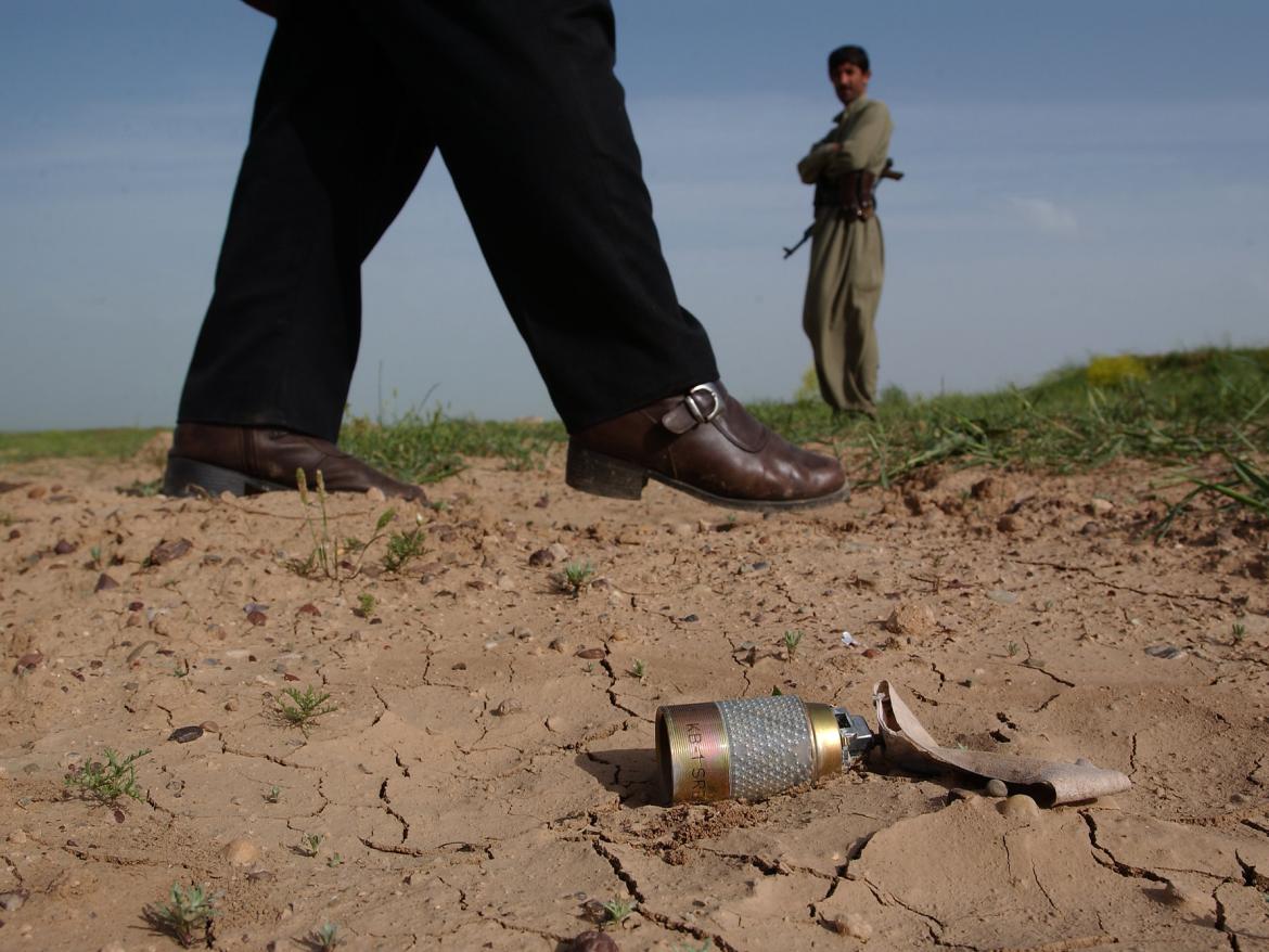 A man walks past an unexploded bomblet in a field. This area near Mosul is littered with US KB1 cluster-bombs. 