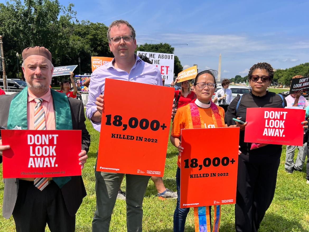 Advocates at rally to end gun violence hold signs that say "don't look away" and "18,000 killed in 2022"