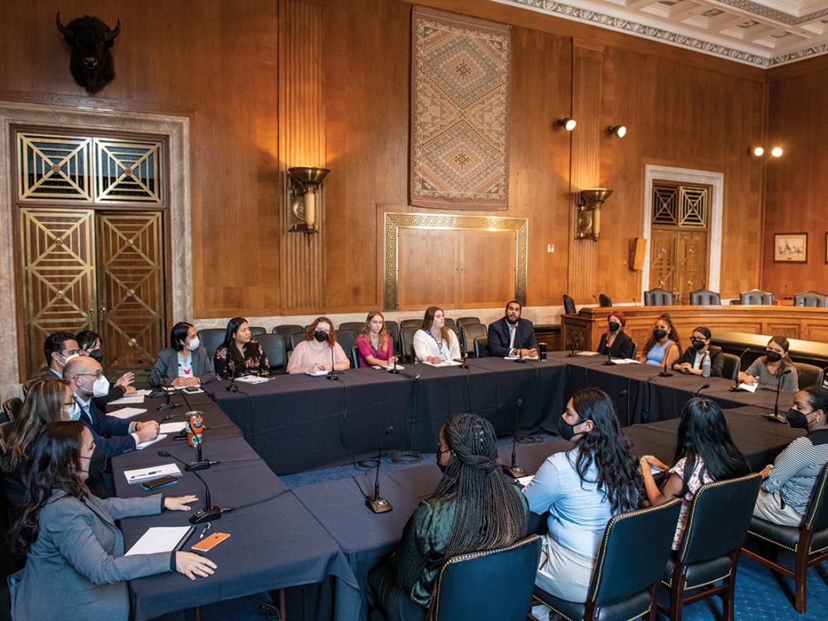 A large group of avocates hold a lobby visit in a Congressional hearing room