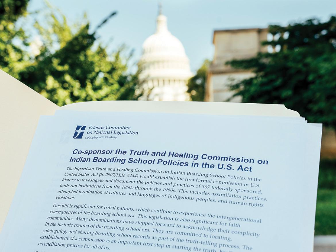 Reading a document in front of the U.S. Capitol. The document is titled: "Co-Sponsor the Truth and Healing Commission on Indian Boarding School Policies in the U.S. Act