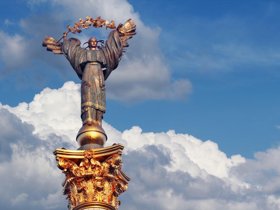 Closeup bronze sculpture of Ukrainian girl with golden garland on column of Independence in Kiev against blue sky