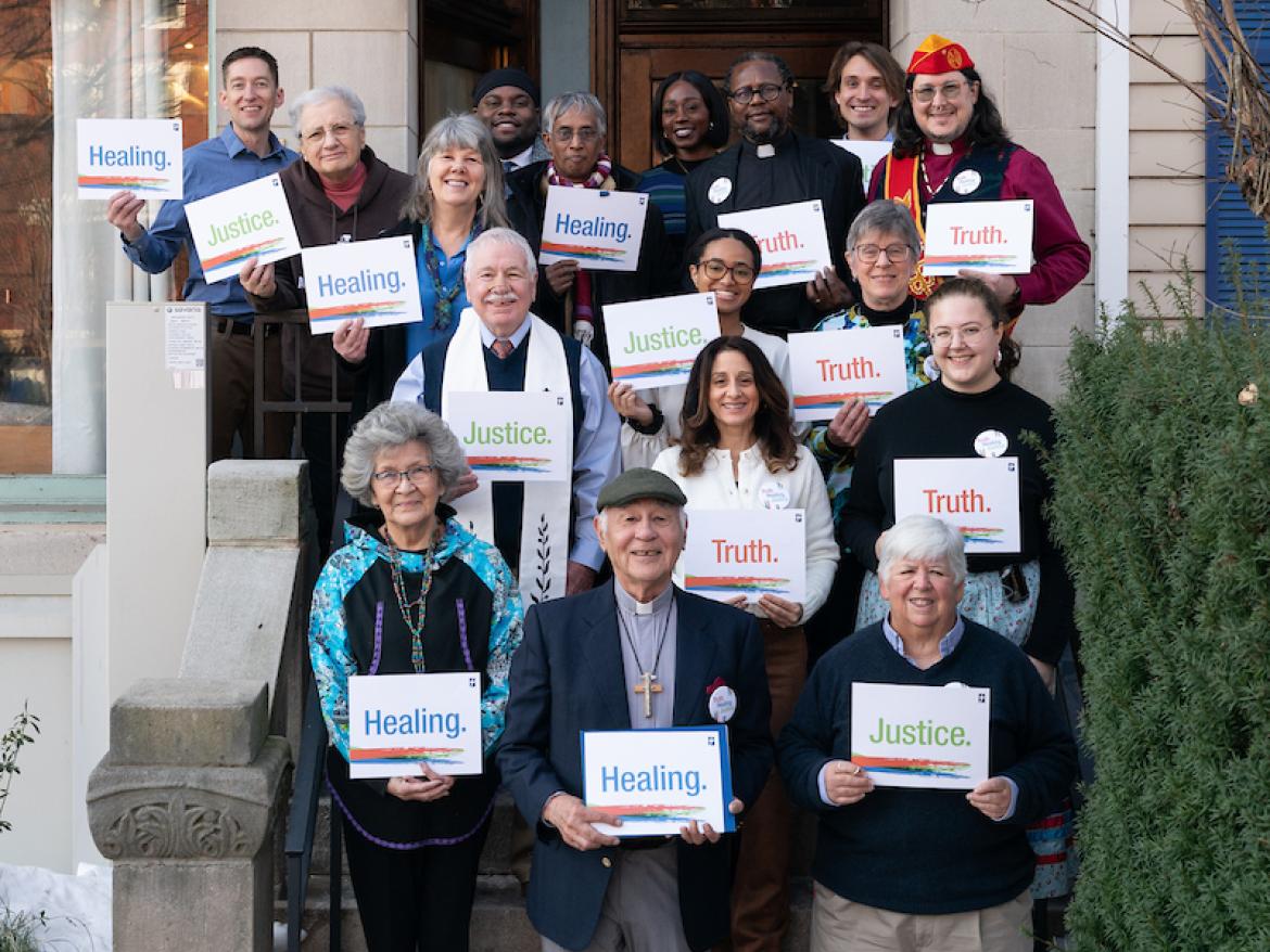 Faith leaders standing on steps with signs saying "Truth + Healing"