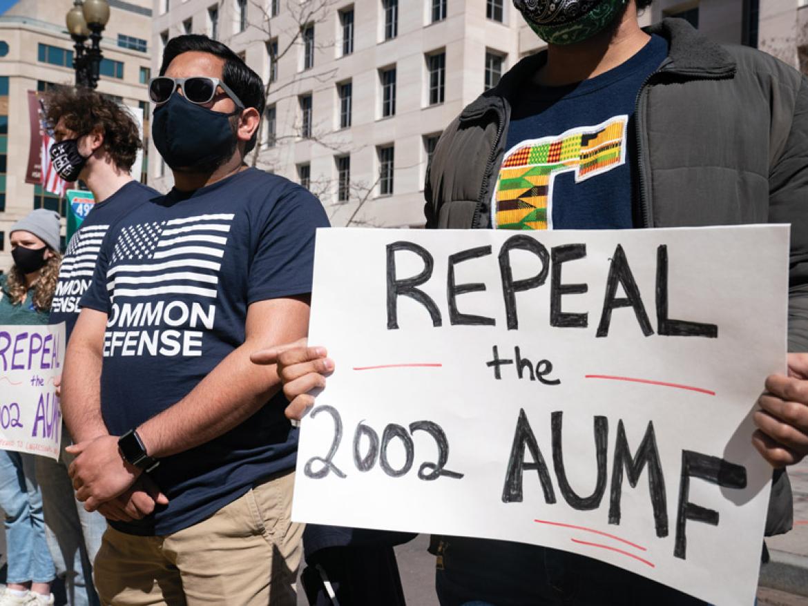 Advocates holding a sign that says "Repeal the 2002 AUMF"
