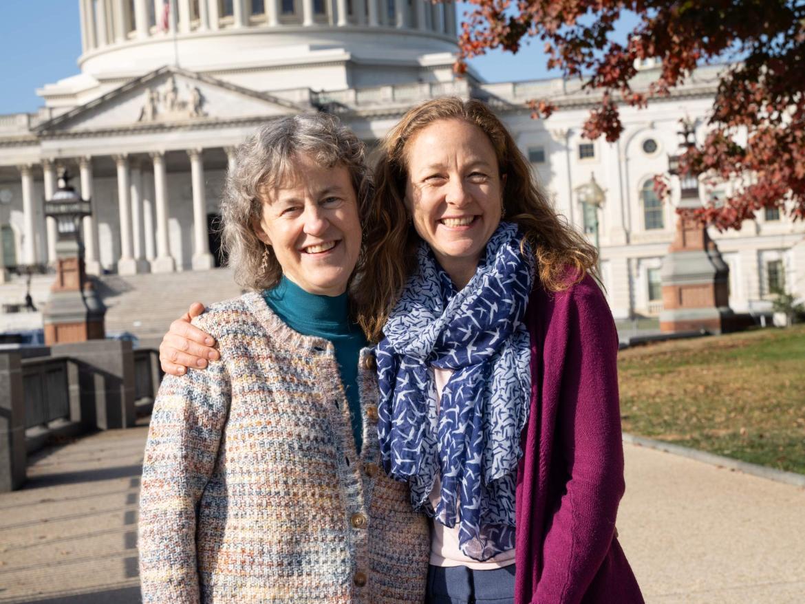 Two women smiling at the camera in front of the U.S. Capitol