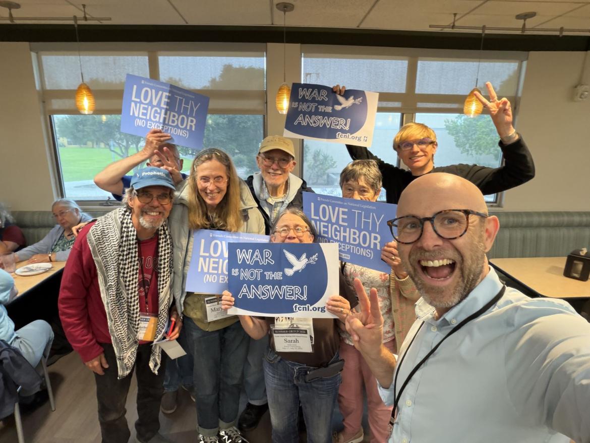 Stephen Donahoe waving a peace sign in front of others with signs