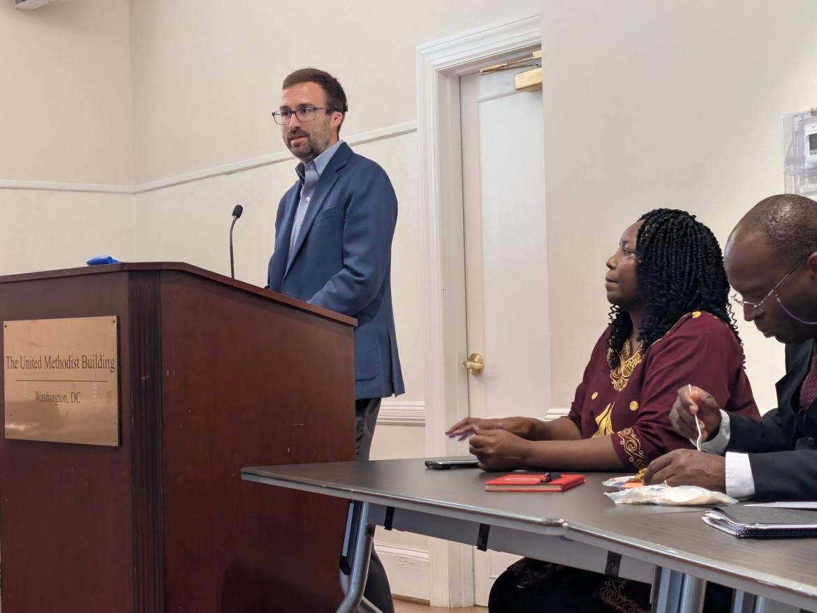 White man in a suit speaking at a podium