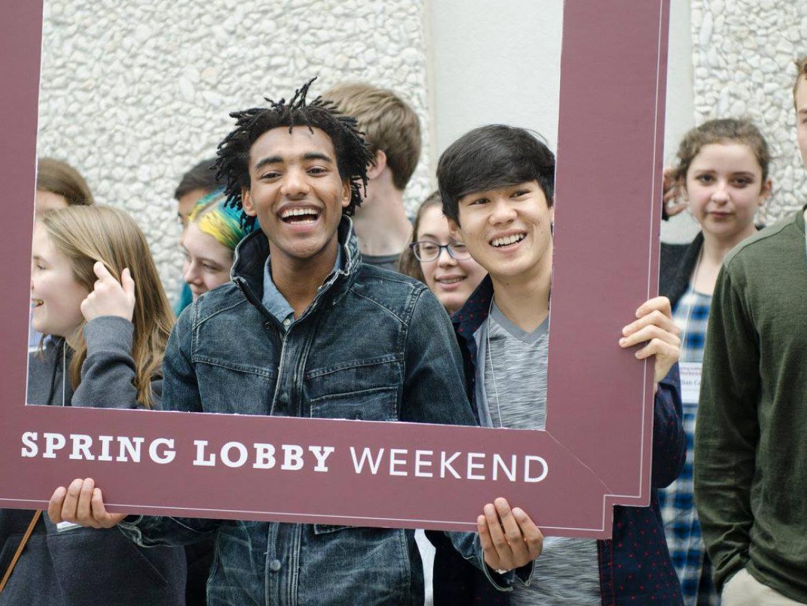 Students hold Spring Lobby Weekend sign