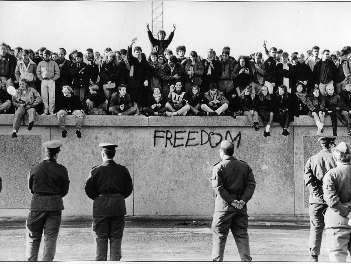 East German students sit atop the Berlin Wall, November 1989.