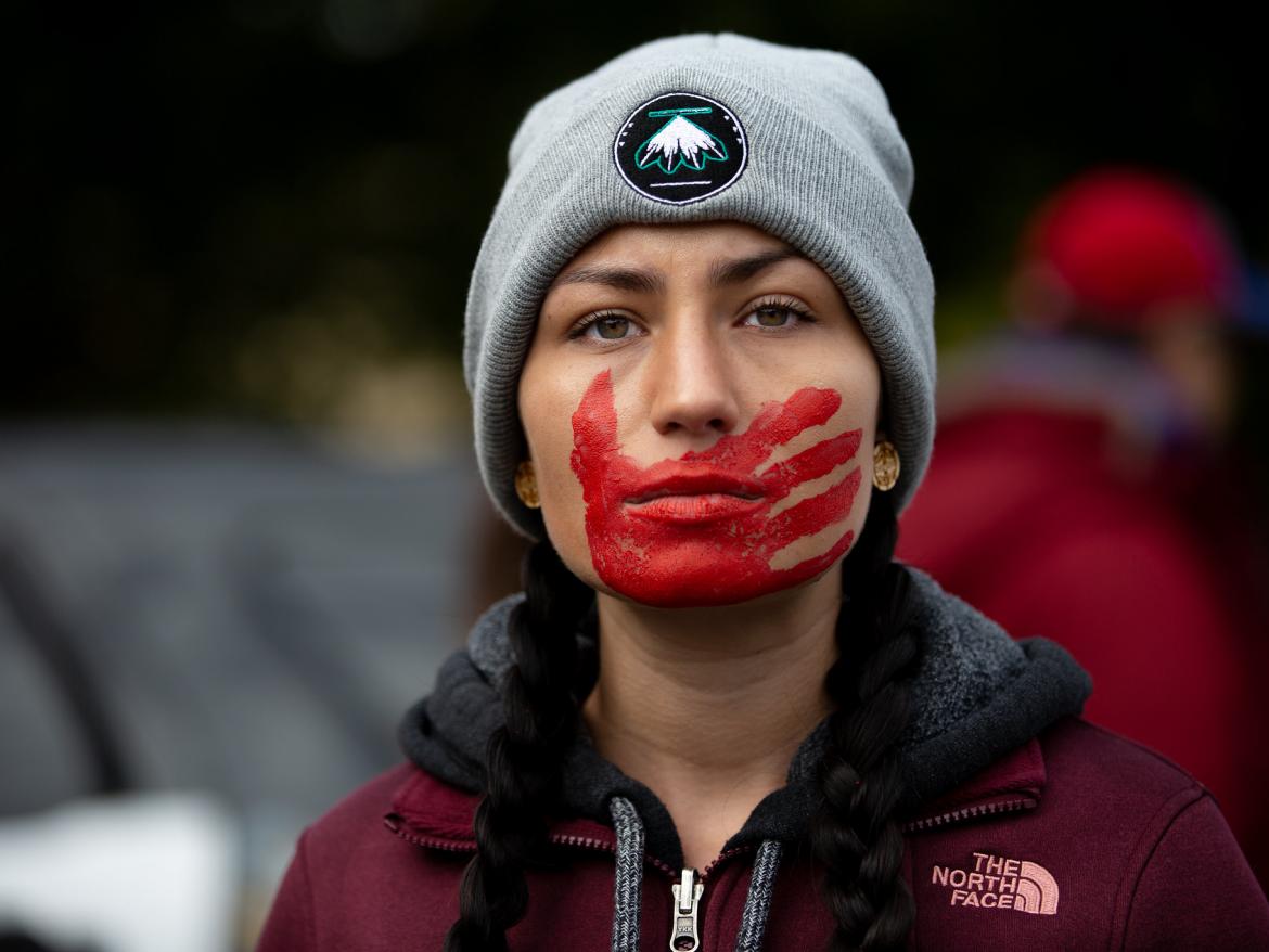 Woman with red hand print over her mouth at a rally in Rochester, NY. 2019