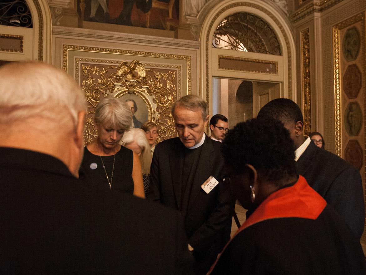 Diane Randall prays with faith leaders and members of Congress.