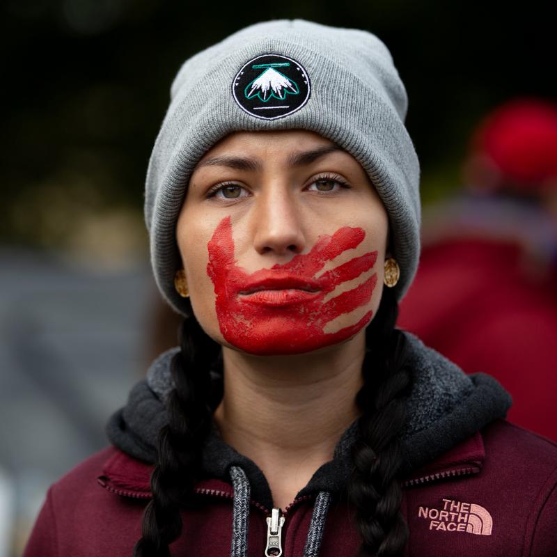 Woman with red hand print over her mouth at a rally in Rochester, NY. 2019