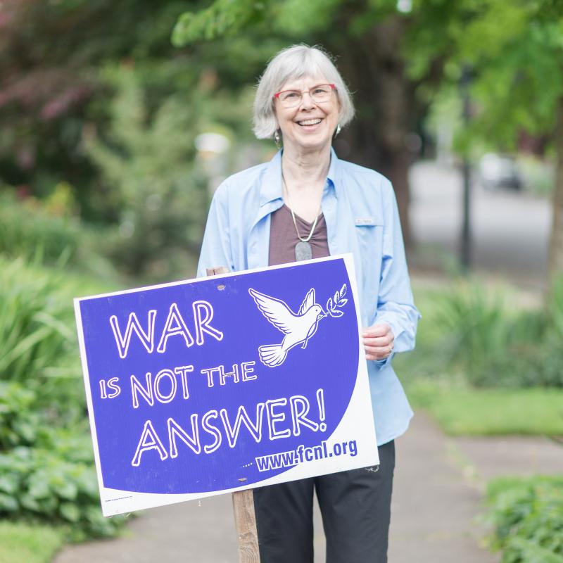 Marge Abbot holding sign that says "War is Not the Answer"