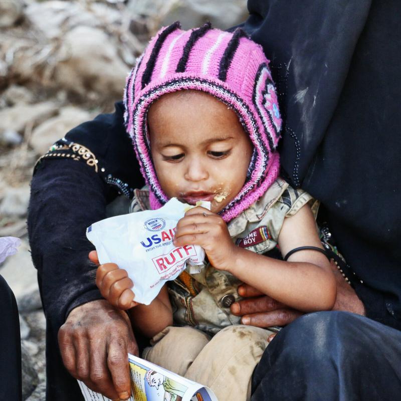 A child in Yemen eats a ready-to-use therapeutic food bag