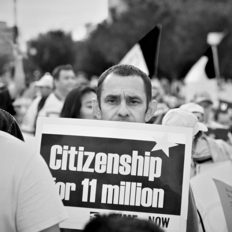 Man holding sign at rally that says "Citzenship for 11 Million"