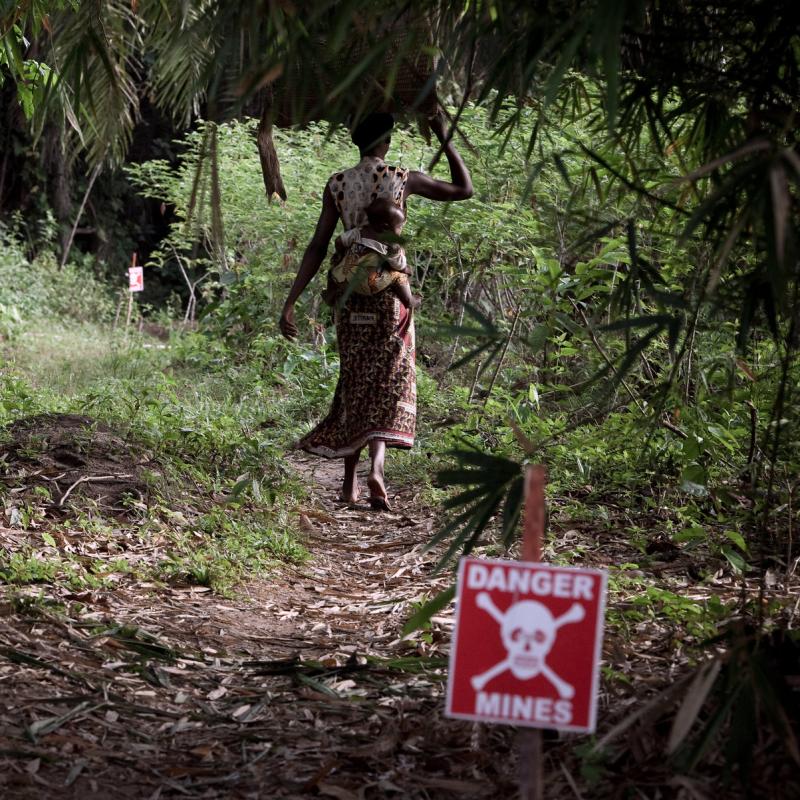 A woman from Tshamaka village walks into the forest on a path marked by MECHEM Demining, a partner of UNMAS, in the Democratic Republic of the Congo. In this area, near the Kisangani airfield, mines and explosive remnants of war contaminate many of the paths and forests. 