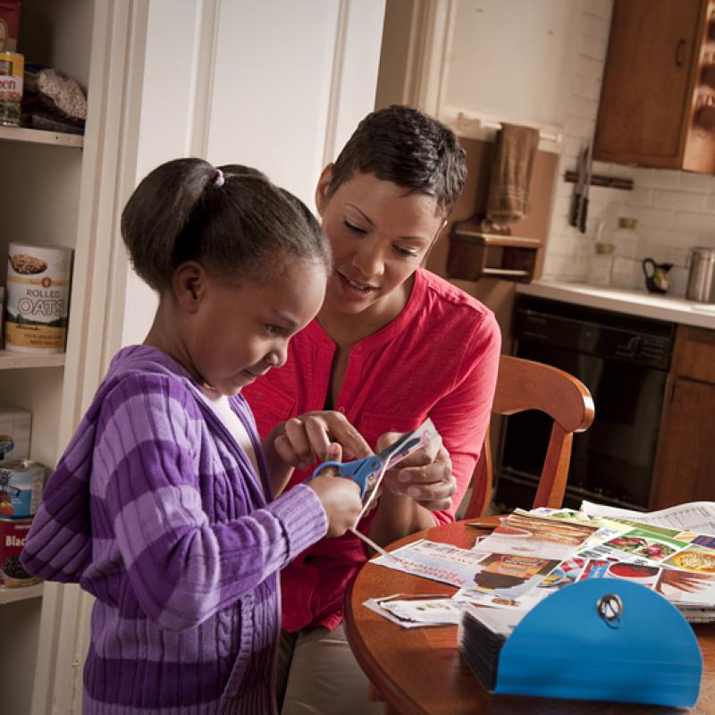 A woman and her daughter look at coupons while preparing a shopping list