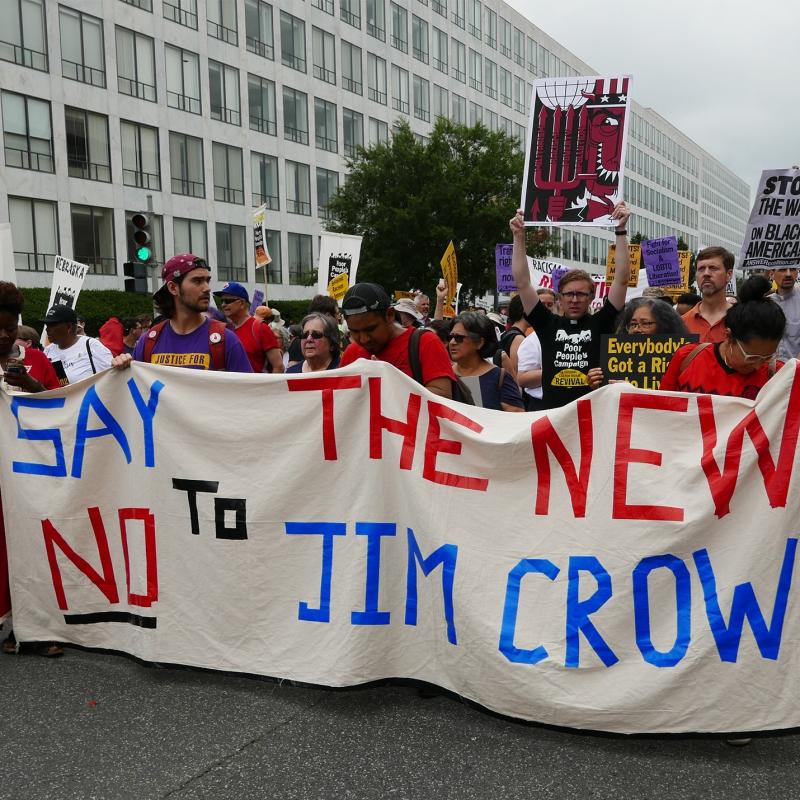 Protestors carry sign that reads: "Say no to the new Jim Crow"