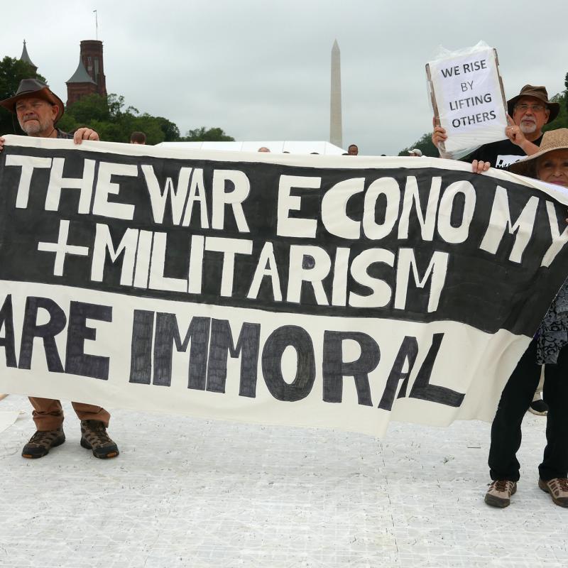 Marches hold sign that says "the war economy and militarism are immoral" at the 2018 Poor Peoples Campaign rally