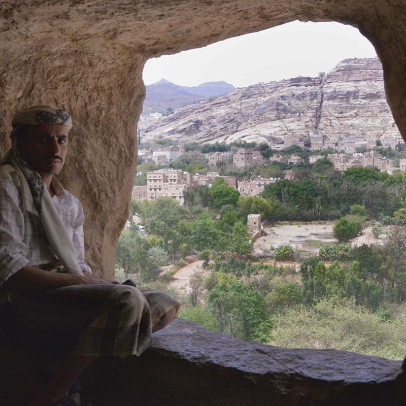 Yemen: Man sitting at mouth of cave overlooking landscape
