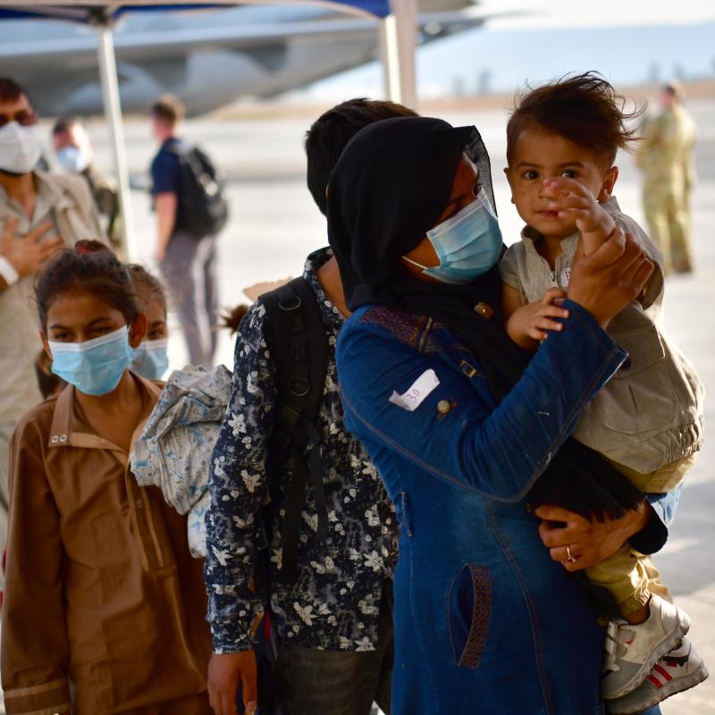 An family of Afghan evacuees waits in line at a U.S. Naval Air Station in Italy