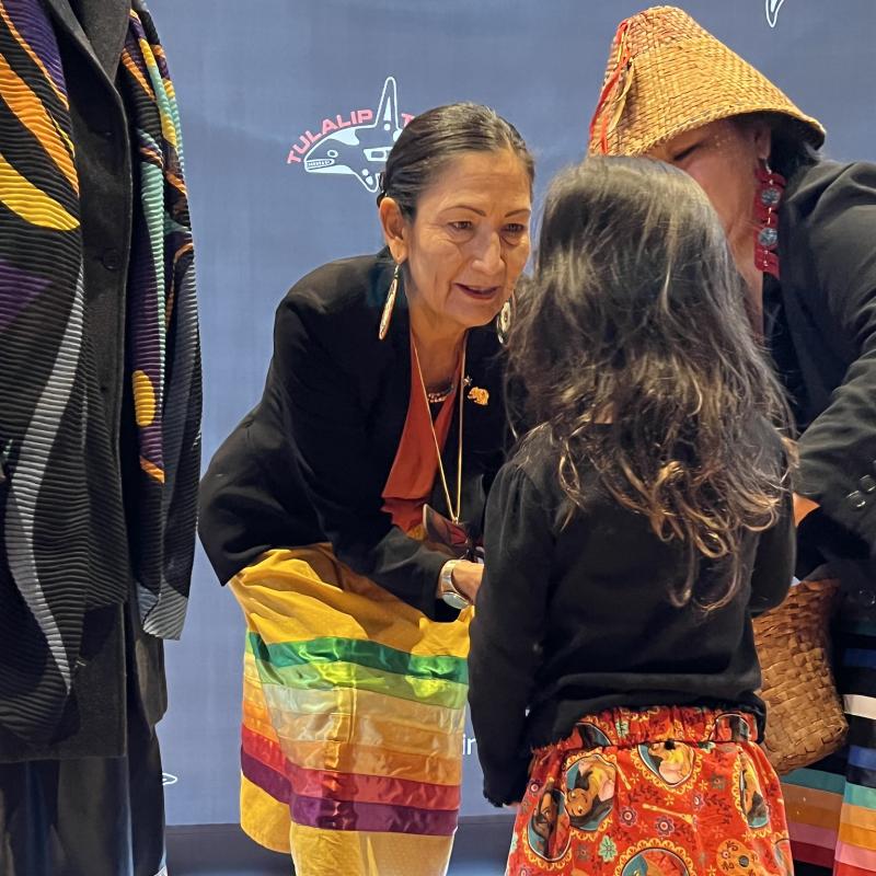 Secretary Den Haaland speaks to a young girl at a stop on the Road to Healing Tour in Tulalip, Washington