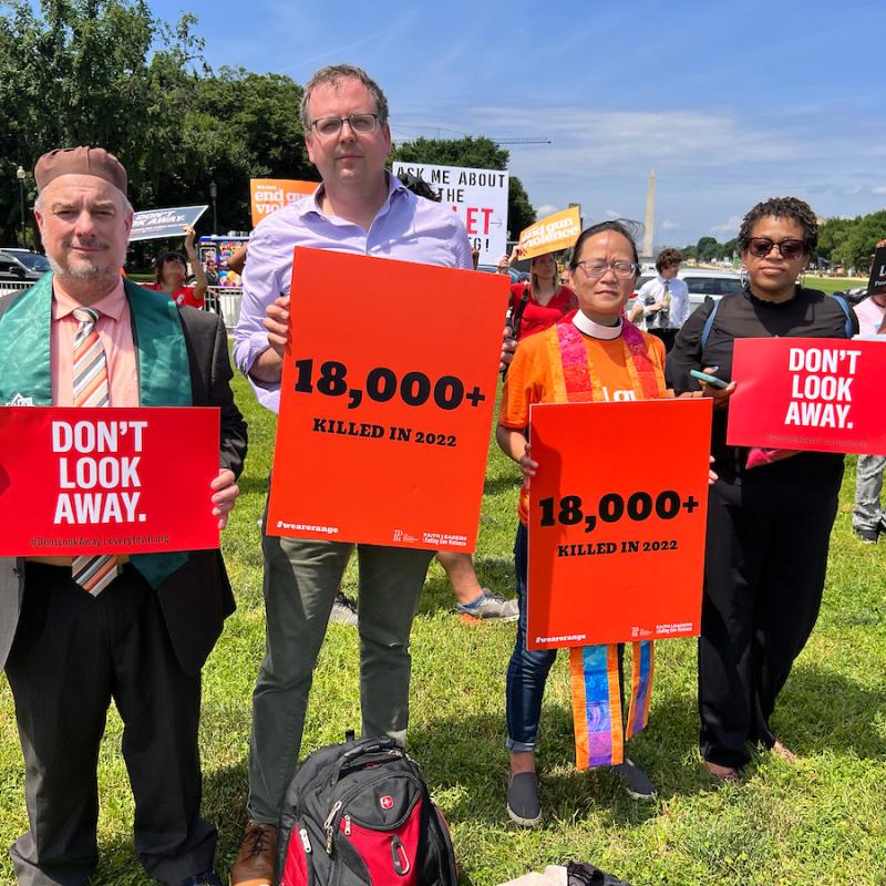 Advocates at rally to end gun violence hold signs that say "don't look away" and "18,000 killed in 2022"