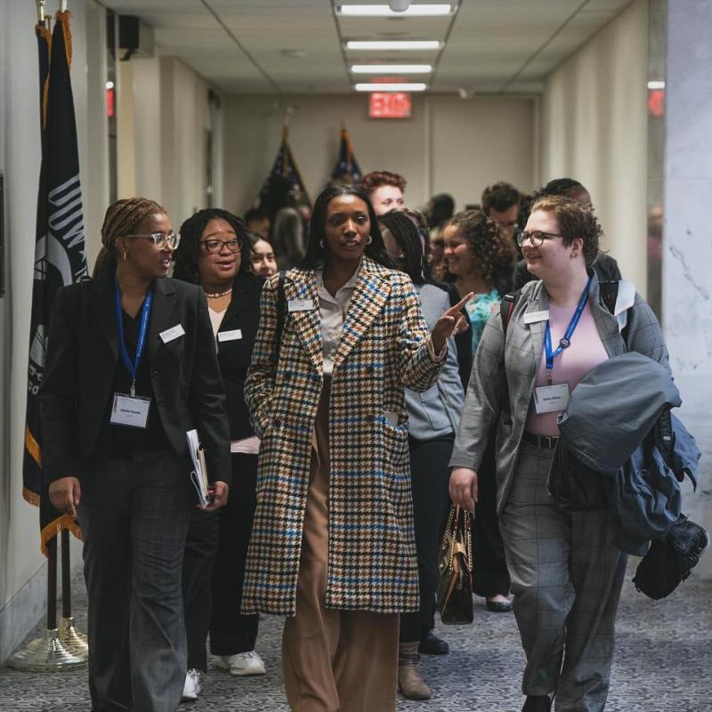 People in coats walking through Capitol corridor