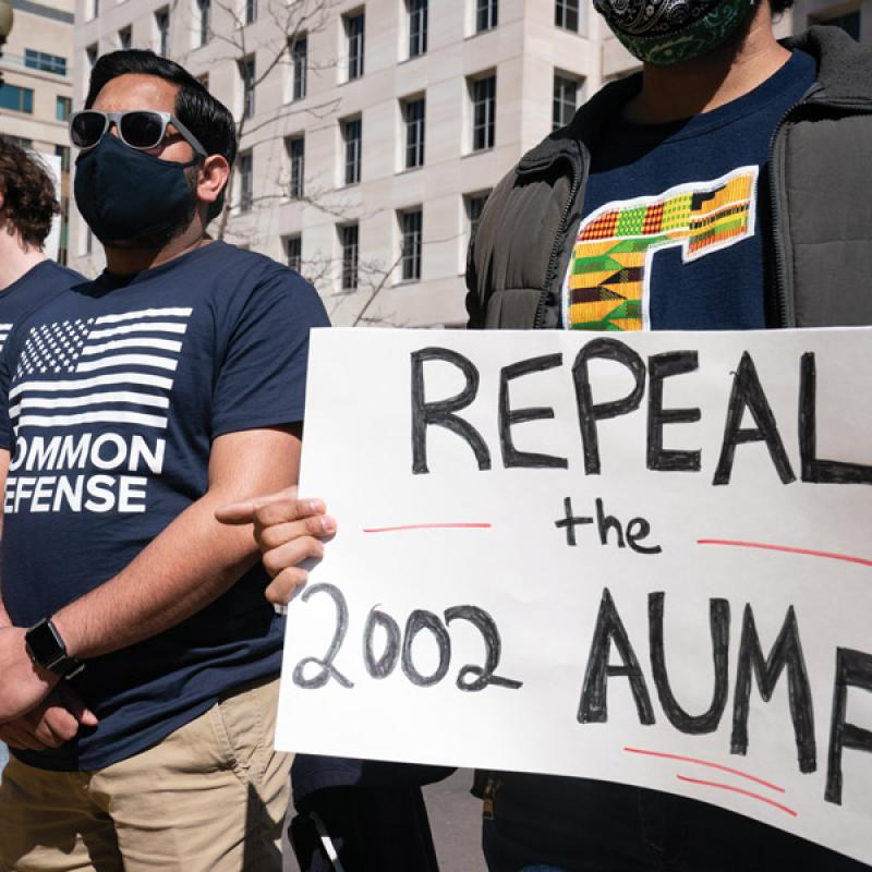 Advocates holding a sign that says "Repeal the 2002 AUMF"