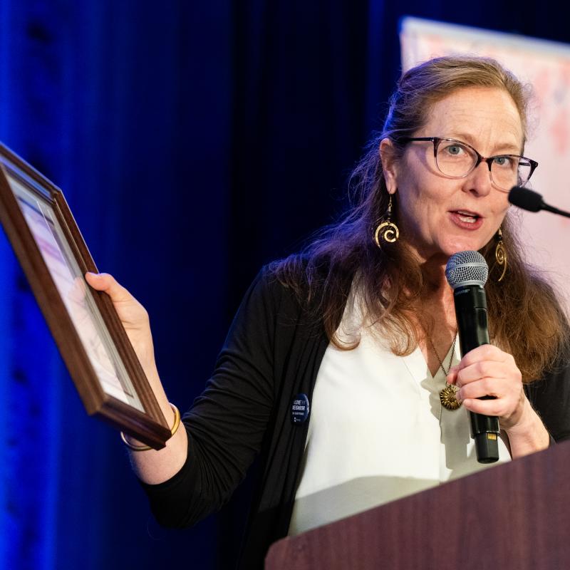 Bridget Moix with award speaking at a microphone