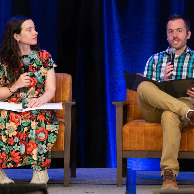 Two people seated on a stage