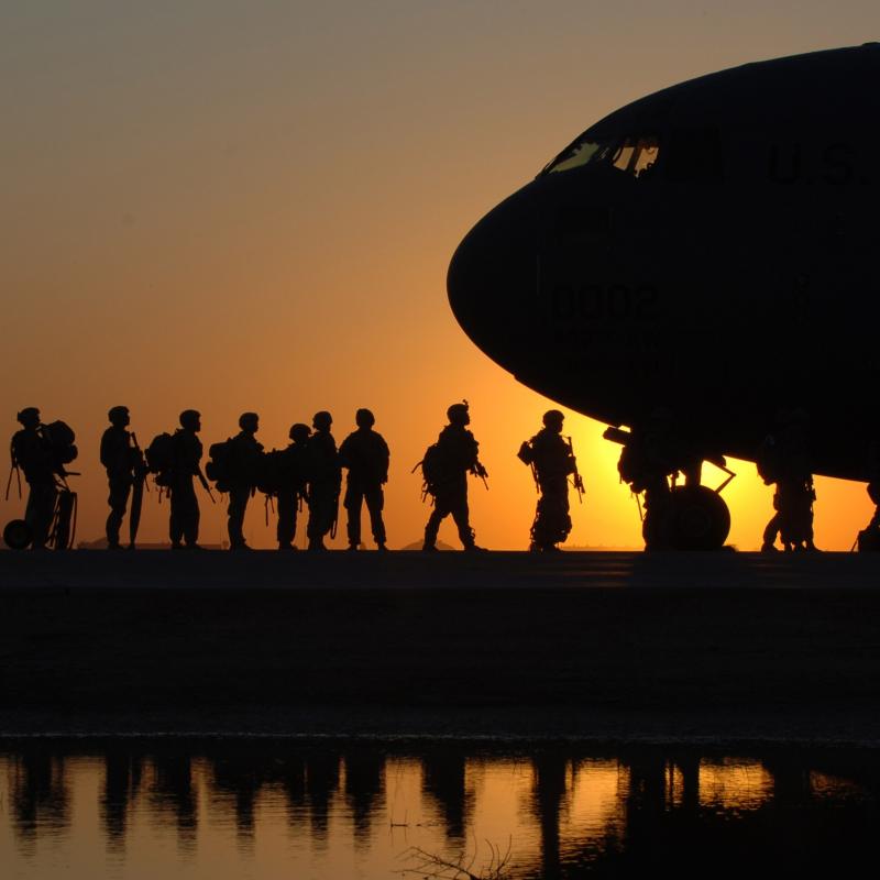 Soldiers boarding plane at sunset.