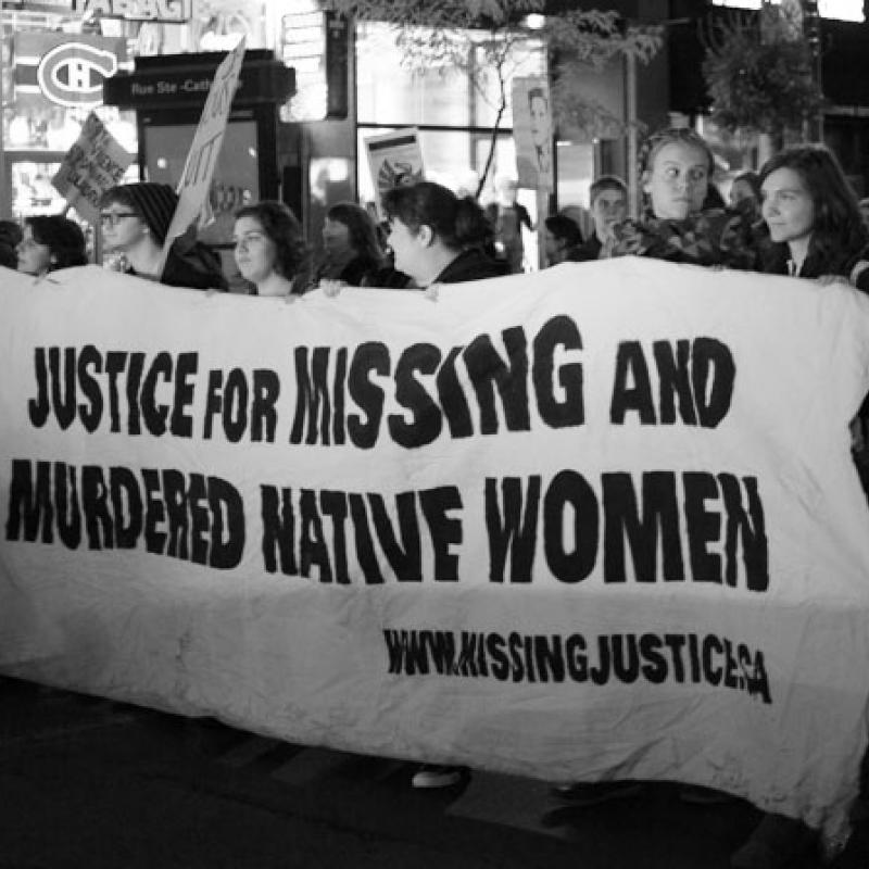 Marchers carrying a sign that says "Justice for Missing and Murdered Native Women"