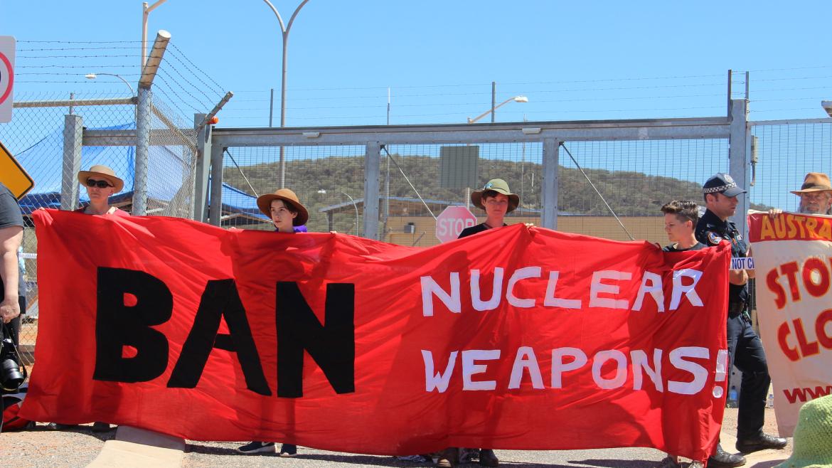 Portestors hold banner that reads, "Ban Nuclear Weapons"