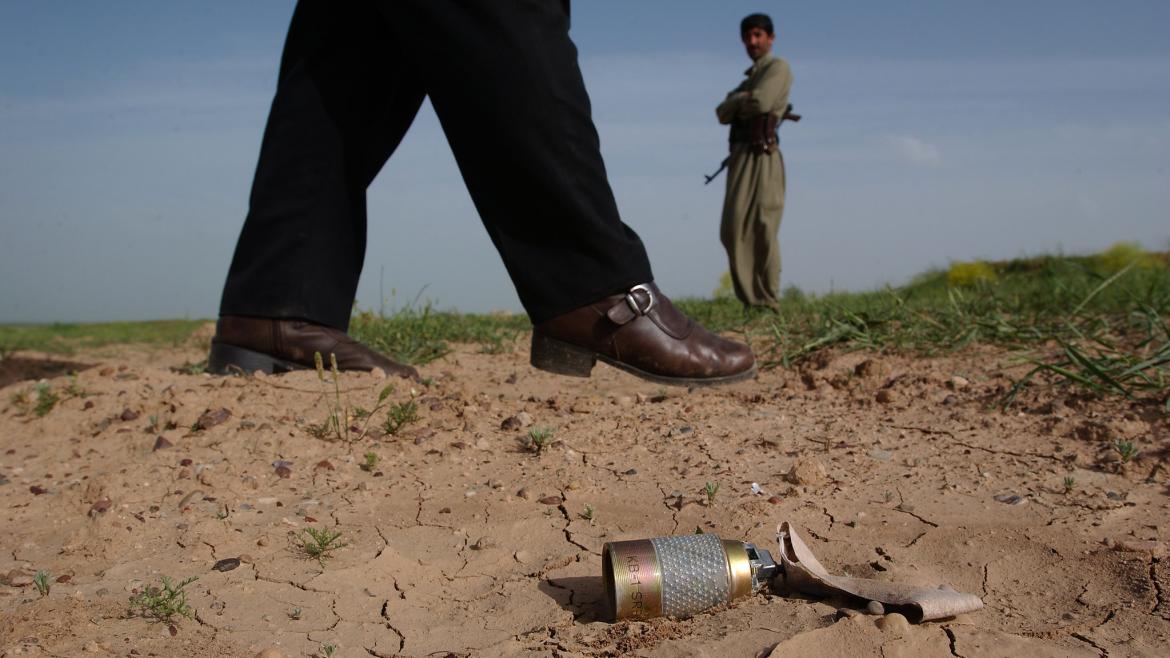 A man walks past an unexploded bomblet in a field. This area near Mosul is littered with US KB1 cluster-bombs. 