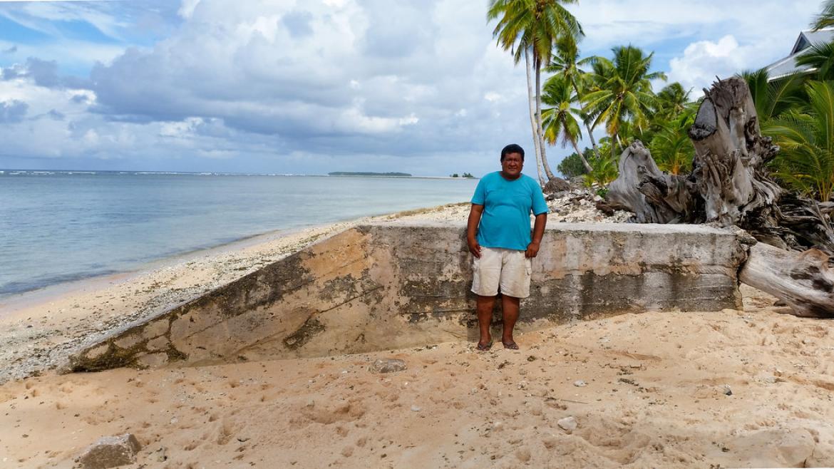 A man stands on the shore next to a concrete barrier. The project is part of the Tuvalu Coastal Adaptation Project to strengthen the resilience of one of the world’s most vulnerable countries to climate change and sea-level rise. 