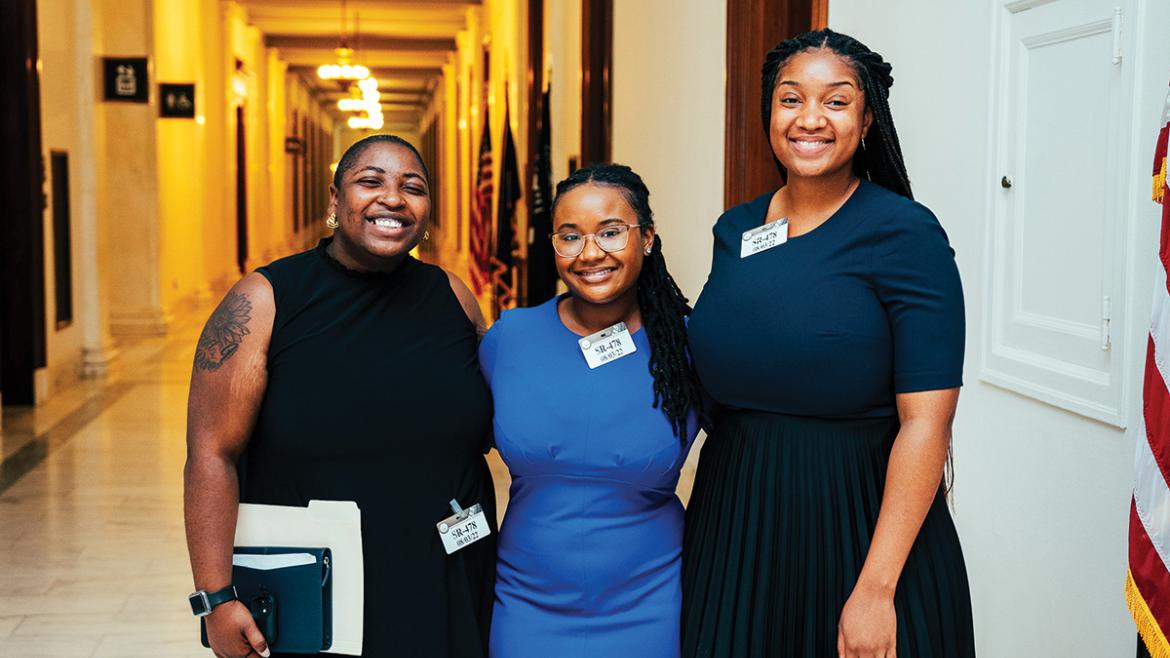 Three young advocates smile in hallway of U.S. Congress
