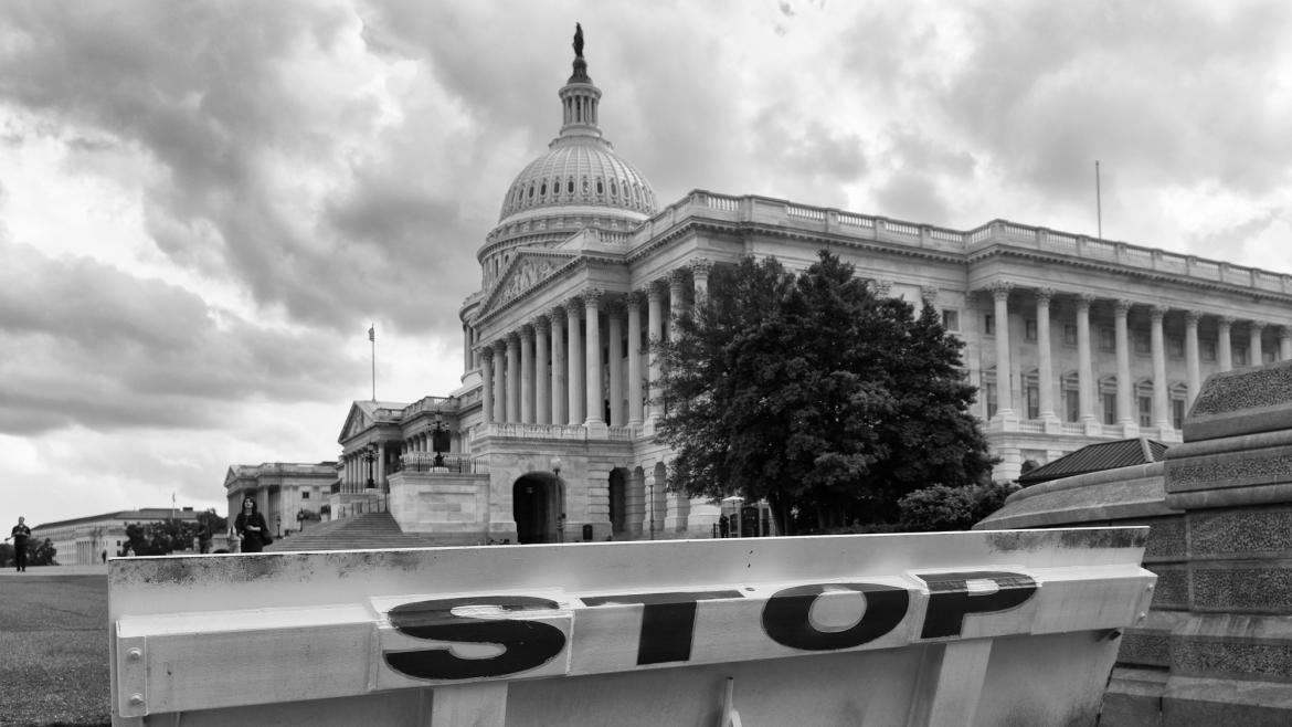 Raised gate in front of U.S. Capitol Building with signage that says "stop"