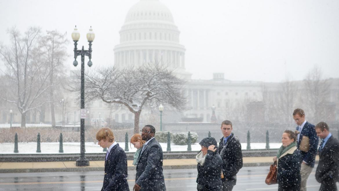 Young adults walk through snow past Capitol